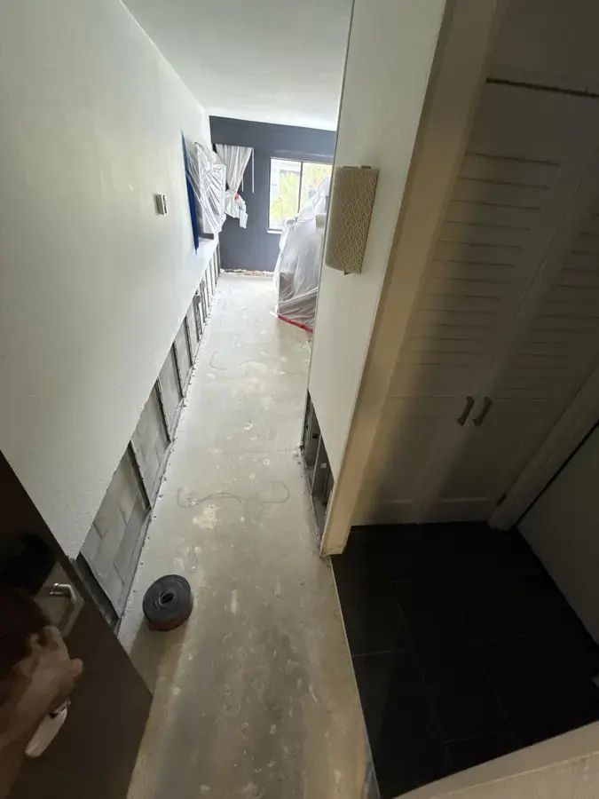 Hallway with the lower drywall cut away and plastic sheeting during drying in Lancaster