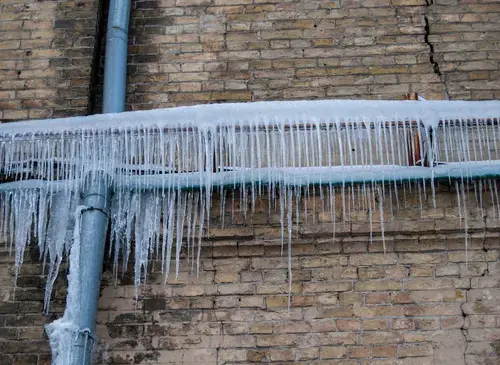 Icicles hanging from a frozen pipe along a brick wall during a hard freeze near Lancaster, SC